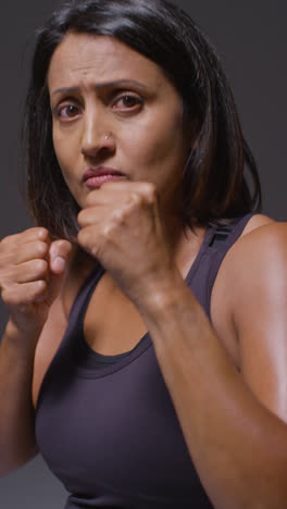 Retrato-De-Estudio-De-Vídeo-Vertical-De-Una-Mujer-Madura-Que-Usa-Ropa-De-Gimnasio-Haciendo-Ejercicio-De-Sparring-En-La-Cámara-1